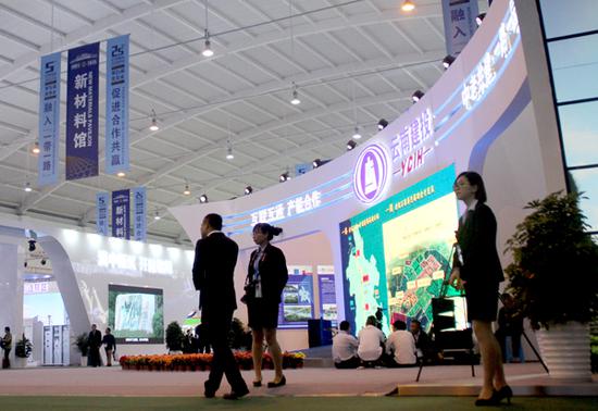A visitor (left) walks past a booth at the fifth China-South Asia Expo on June 14 in Kunming, capital of Yunnan province. (Photo by Shi Wenzhi/China Daily)