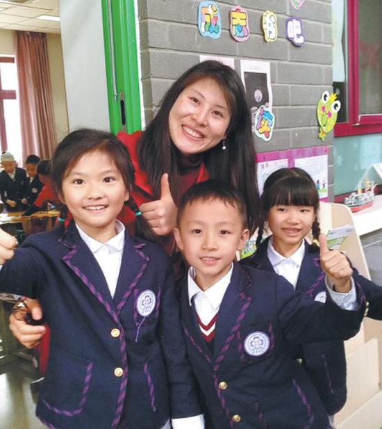 Wang Jing, English teacher of second-graders at the Tsinghua-affiliated elementary school, poses with students.  (Photo provided to China Daily)