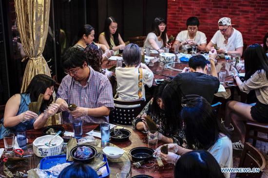 People learn how to make Zongzi, or rice dumplings, at a workshop in a restaurant in Manhattan, New York City, the United States, on June 16, 2018. A famed restaurant in New York City turned itself into a workshop over the weekend for learning to make rice dumplings to celebrate the Dragon Boat Festival, a traditional Chinese holiday that commemorates the death of an ancient patriotic poet Qu Yuan. (Xinhua/Li Muzi)