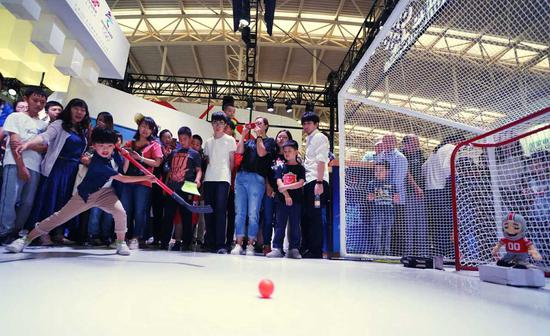 Visitors watch a robot goalkeeper in action during an industry expo related to 5G, which was held in Tianjin. (Photo by Li Shengli/For China Daily)