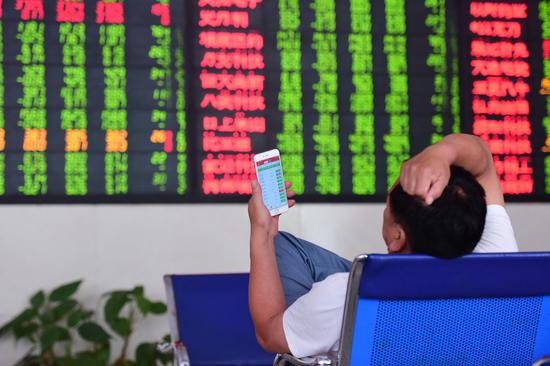 An investor checks stock prices at a brokerage in Fuyang, Anhui province. [Photo by Lu Qijian/For China Daily]