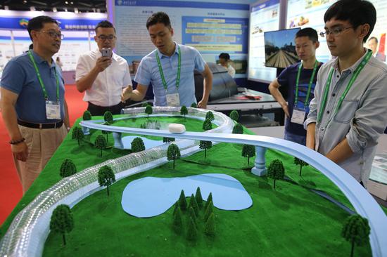 Visitors observe the model of a superconducting tube maglev at the 2018 World Transport Convention in Beijing on Tuesday. （WANG JING/CHINA DAILY）