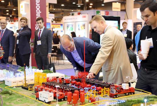 U.S. businessmen show interest in the booth of a Chinese enterprise during an oil expo in Houston, the United States. (Photo by Wang Huan/China News Service)