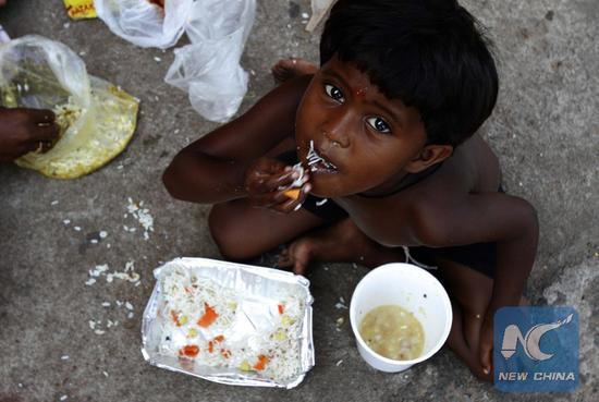 File Photo: A child of a street bagger family eats gifted food on the World Food Day in the eastern Indian state Orissa's capital city Bhubaneswar, Oct. 16, 2014. (Xinhua/Stringer)