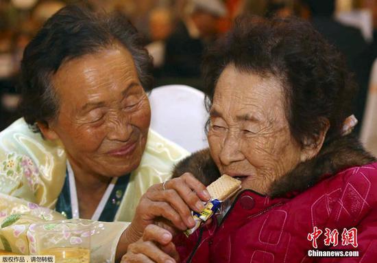 Kim Ri Nam, 83, (left), who lives in DPRK, gives a cookie to her South Korean older sister, Kim Yu-nam, 89, during the reunion of separated families held at DPRK's Diamond Mountain resort on October 24, 2015. (Photo/Agencies)