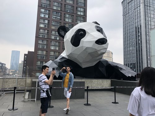 Tourists take photos in front of the giant panda sculpture on top of International Finance Square, in Chengdu's Chunxi Road business district on June 15. The sculpture, named 