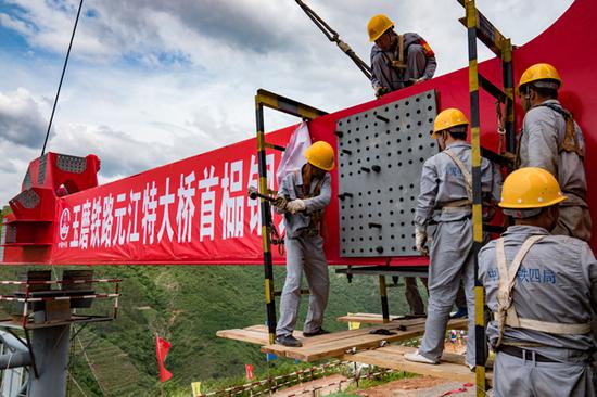 Builders install the first steel truss complex on Friday at Yuanjiang Railway Bridge, part of the Chinese section of the China-Laos railway, a major project in the Belt and Road Initiative. [Photo by Zhu Xiaochen/For China Daily
