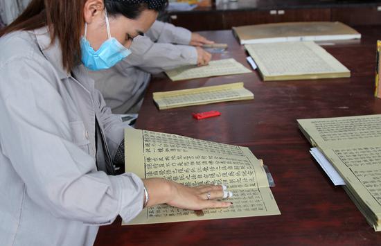 Employees prepare printed copies of the Buddhist classics at Yangzhou Classics Reproductions Co on Wednesday. (Photo/CHINA DAILY)