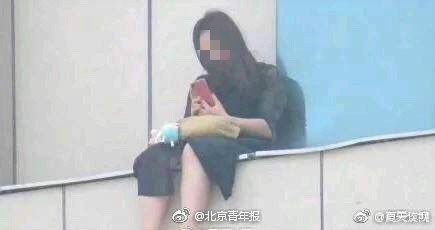 Li is seen sitting on a ledge for hours. (Photo/Beijing Youth Daily via Sina Weibo)