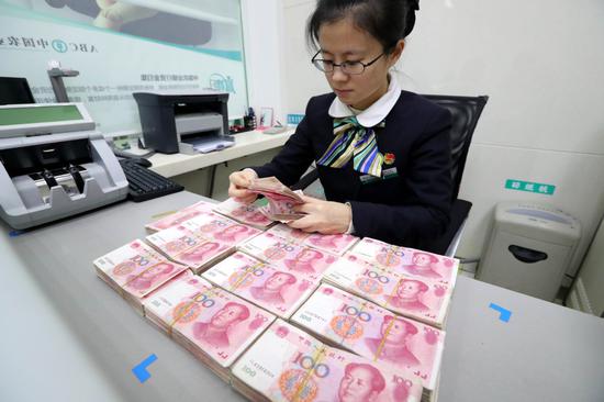 A clerk counts cash at a bank in Huaibei, Anhui Province. (Photo provided to China Daily)