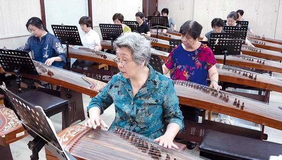 Students learn to play traditional Chinese musical instruments at a school for the elderly on Nantangbang Road in Shanghai. (Photo by Gao Erqiang/China Daily)