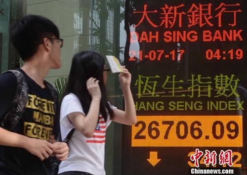 Two passers-by look at the Hang Seng Index on a board in Hong Kong. (File photo/China News Service)