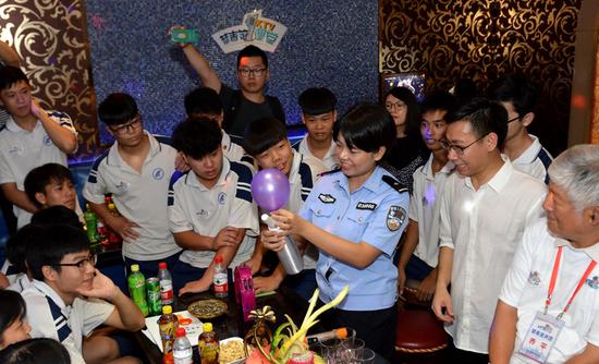 A police officer teaches teenagers a lesson on keeping away from drugs at a karaoke bar in Guangzhou, Guangdong Province, on Tuesday. She advised the teens to raise their awareness of drugs－even anesthetics such as nitrous oxide, or laughing gas－which is being abused as a drug and may be found in balloons at entertainment venues. (QIAN WENPAN/FOR CHINA DAILY)