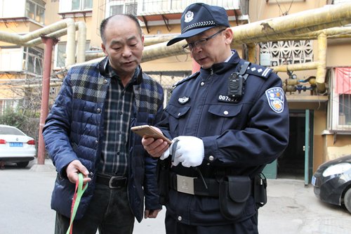 Chen Zhao, a Ji'nan police officer, checks a dog owner's information through the new mobile application in Ji'nan, capital of East China's Shandong Province, in March. (Photo/ Courtesy of Ji'nan Public Security Bureau)