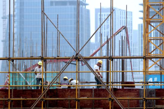 Builders work at a property construction site in Huai'an, Jiangsu Province. (Photo by Zhou Changguo/For China Daily)