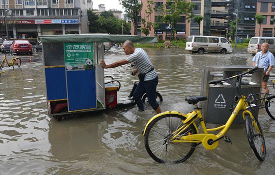 A man pushes his vehicle in a flooded street in Chengdu, Sichuan Province, on Thursday. (PHOTO/CHINA NEWS SERVICE)