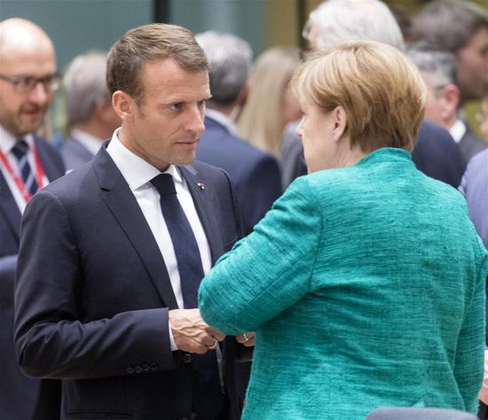 French President Emmanuel Macron (L) and German Chancellor Angela Merkel talk at the first day of a two-day EU Summit in Brussels, Belgium, June 28, 2018.(Xinhua/Thierry Monass)