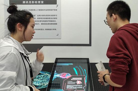 A Tencent engineer (left) demonstrates the company's AI product that helps patients with an early and accurate diagnosis. (Photo provided to China Daily)