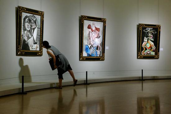 A visitor looks at a painting by Pablo Picasso at the exhibition at the National Art Museum of China. (Photo by Jiang Dong/China Daily)