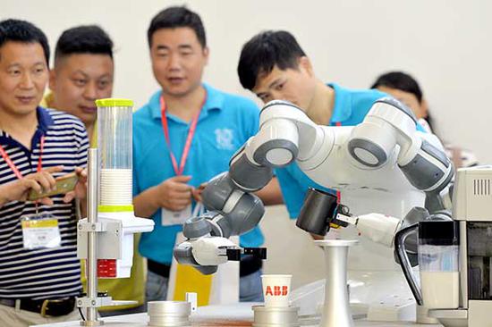 YuMi, a robot produced by ABB, makes coffee for visitors at a fair in Wuhan, Hubei province. （Photo by Zhou Chao/for China Daily）