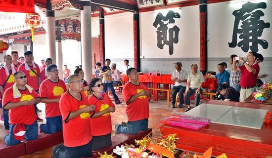  Huang Chi-tsung (front left) and members of his extended family pray in the Huang ancestral temple in Pujin, Fujian province. (Photo for China Daily/Lu Junjie)