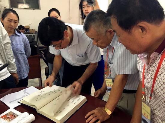  Huang Ching-hsiung (second from right) examines genealogical records related to his family in Pujin. (Photo for China Daily)