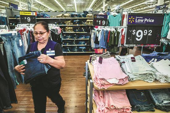 An employee arranges clothing at a Walmart Inc store in Secaucus, New Jersey. Walmart is expected to be hit if a trade war starts. (Photo provided to China Daily)