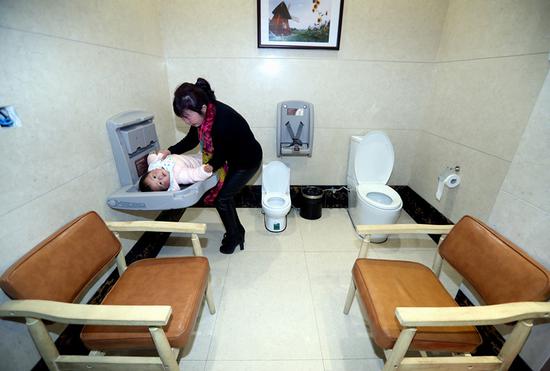 A woman attends to a baby in a public toilet in a village of Yongkang, Zhejiang Province, in January. (LIN YUNLONG/FOR CHINA DAILY)