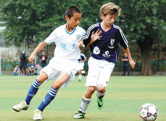 Young soccer players from Dongbeilu Primary School in Dalian and the Mercer Island United club in the United States play a friendly game on July 30, 2014. (Photo by Zhang Xiaomin/China Daily)