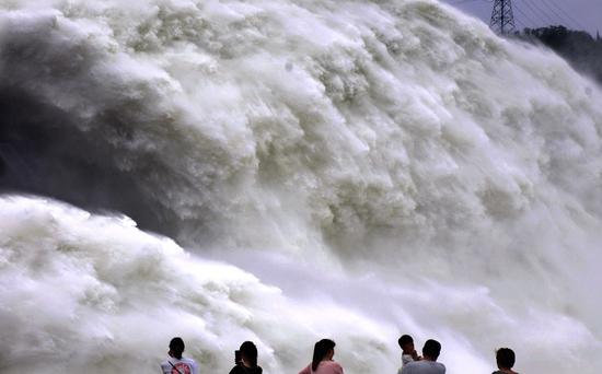 Tourists watch as water is discharged from Xiaolangdi Reservoir in Jiyuan, Henan Province, on Tuesday. The discharge will allow more room behind the dam to capture floodwaters. (Photo/Xinhua)