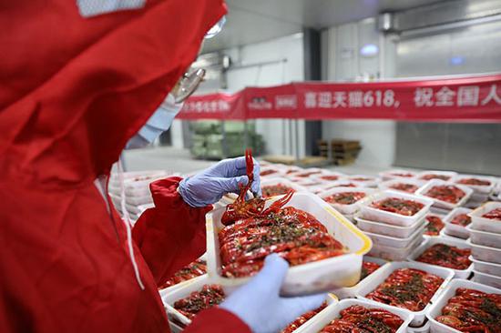 Qu Yunxiao, a professional taster and crawfish quality supervisor in Xinliangji, a crawfish processing company in Hubei province, has checked tens of thousands of crawfish every day since the kick off of the FIFA World Cup amid the peak sales season for crawfish around China.(Photo provided to China Daily)
