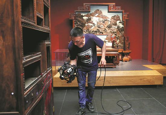 A staff member of the Palace Museum takes measurements of a piece of royal furniture from the Qing Dynasty (1644-1911) on Friday. JIANG DONG / CHINA DAILY