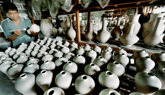 Craftsman Wang Aiping dusts the dry porcelain embryo. (Photo by Zhuo Zhongwei and Li Housheng/Asianewsphoto)