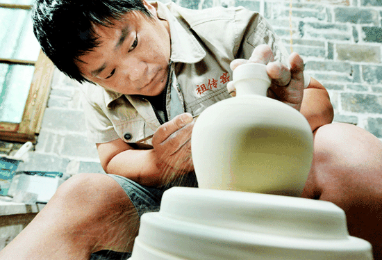 Peng Siyi, a Zuchuan kiln craftsman, repairs a porcelain embryo on July 1 in Poyang county, Jiangxi province. (Photo by Zhuo Zhongwei and Li Housheng/Asianewsphoto)