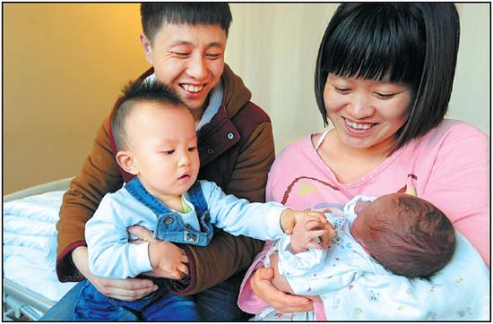 A couple both born in the 1990s hold their children, an infant daughter and her 18-month-old brother, in Shenyang, Liaoning province, on Jan 3, 2016. (Photo by Li Hao/For China Daily)
