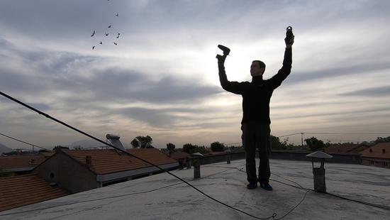 Colin Chinnery records pigeon whistles on top of a building in Beijing. (Photo/China Daily)