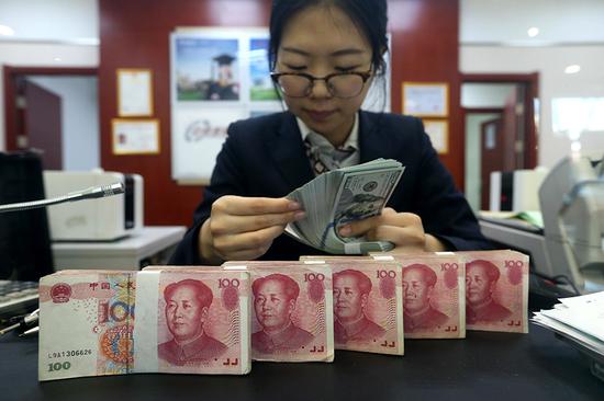 A clerk counts US dollars at a bank in Taiyuan, capital of Shanxi Province. (Photo/China News Service by Zhang Yun/)