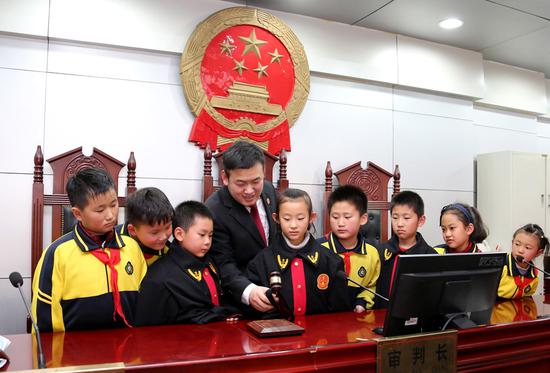 Gao Guangshi, a judge at Shizhong district court, Zaozhuang city, Shandong province, shows primary school students how he uses his gavel. Students are regularly invited to visit the court to learn about proceedings and take part in mock trials. (Photo: For China Daily/Ji Zhe)