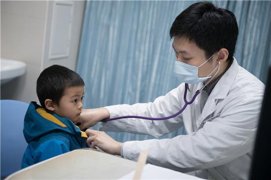 A pediatrician checks a child at Guangzhou Women and Children's Medical Center in Guangdong province in January. (Photo for China Daily)