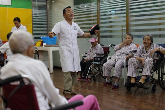 Ouyang Zifan, a carer at Songtang, sings for senior patients. (Photo: China Daily/Wang Jing)