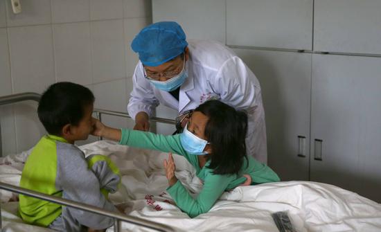 Zhang Yungui, a doctor from the Yunnan AIDS Care Center, checks a patient. [Photo: China Daily/Zou Hong)