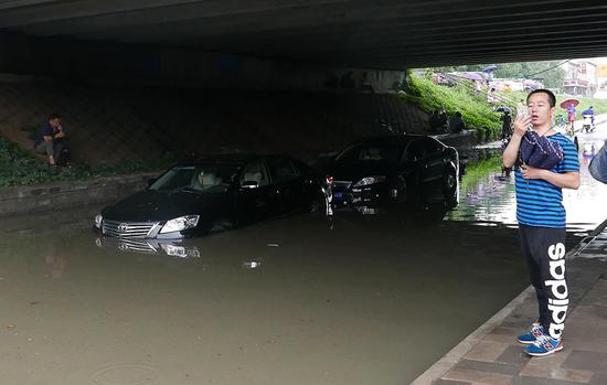 Two cars are stuck under a bridge in the Huilongguan residential area of Beijing on Monday morning. Intense rainfall earlier in the day flooded the passage. (Photo by Jiang Wenjie/For China Daily)