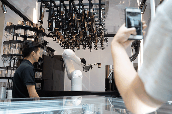 A robotic arm serves a cup of coffee to a customer at Ratio, a new pop-up store at the K11 Art Mall in downtown Shanghai, last month. The robot can make two cups of latte within 90 seconds. A seasoned barista would need at least a minute to make just one cup. (GAO ERQIANG/CHINA DAILY)