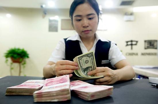 A clerk counts US dollars at a bank in Taiyuan, capital of Shanxi province. (Photo by Zhang Yun/China News Service)