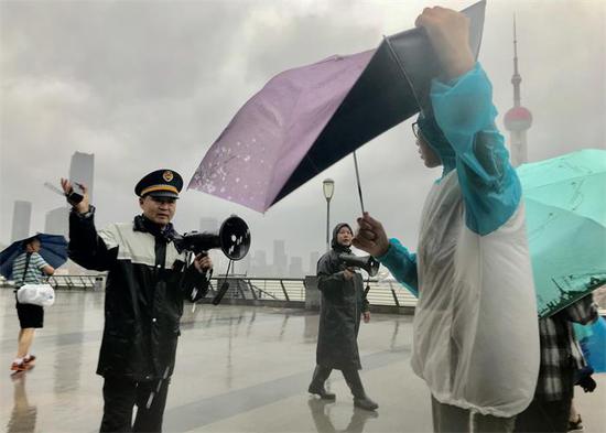 Authorities urge visitors at the Bund in Shanghai to leave for safer places on Sunday. Ampil, the 10th typhoon of the year, hit coastal areas of China with heavy rain. (LIU XIN / FOR CHINA DAILY)