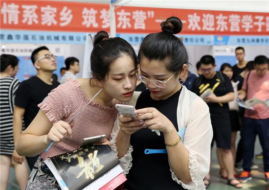 Job seekers share employment information at a job fair in Dongying, Shandong Province, on July 15. (Zhou Guangxue/For China Daily)
