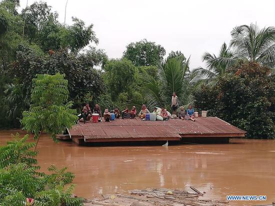 Villagers are seen stranded on rooftop of a house after an under-construction dam collapsed in Attapeu, Laos, on July 24, 2018. (Xinhua/Vilaphon Phommasane)