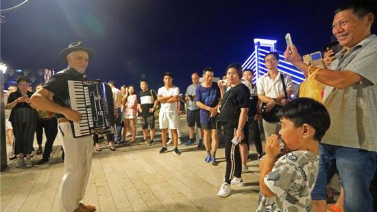 Jon, a Spanish accordionist, entertains the crowd at an art district in Ningbo City. /Photo via People.cn