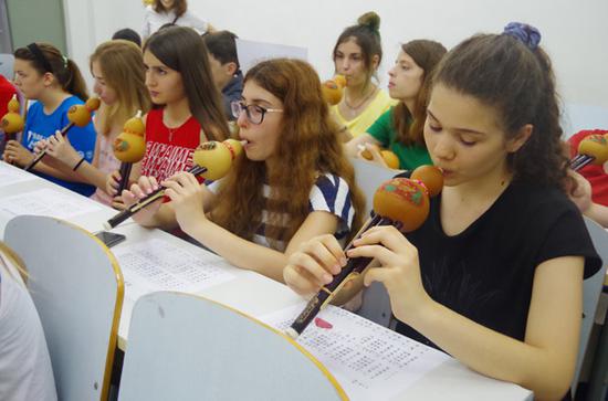 Teenagers from Europe learn to play the hulusi, a traditional musical instrument of the Dai ethnic group in China, at a recent summer camp in Beijing. (Photo/China Daily