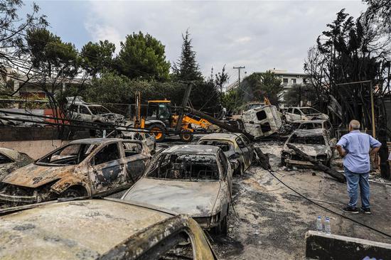A man looks at burned vehicles in Mati, a seaside town east of Athens, Greece, on July 24, 2018. (Xinhua/Lefteris Partsalis)